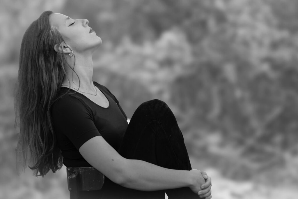 A woman meditates peacefully outdoors with closed eyes, embracing serenity.